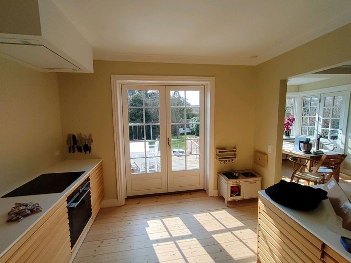 Køkken med beige vægge, hvidt loft og hvide terrassedøre